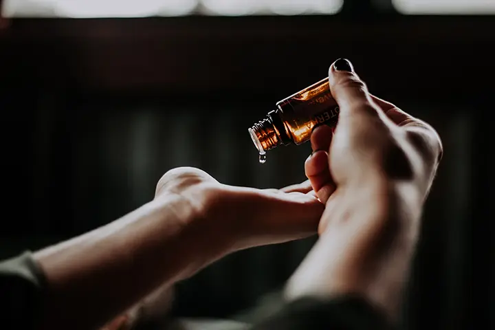 Hand träufelt Flüssigkeit aus Braunglasflasche auf die Haut als Symbol für Supplementierung, Longevity und bewusste Gesundheitspflege